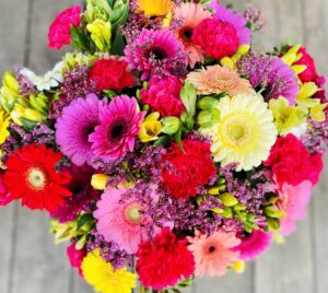 Fargerik blomsterbukett med gerbera og lilla blomster fra Stokkaveien Blomster i Stavanger.