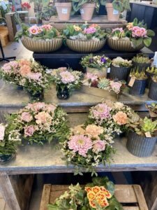 Bord med håndlagde blomsteroppsatser og friske buketter hos Stokkaveien Blomster.